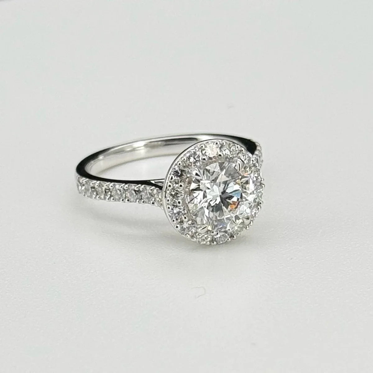 Diamond ring with a halo on a light gray background